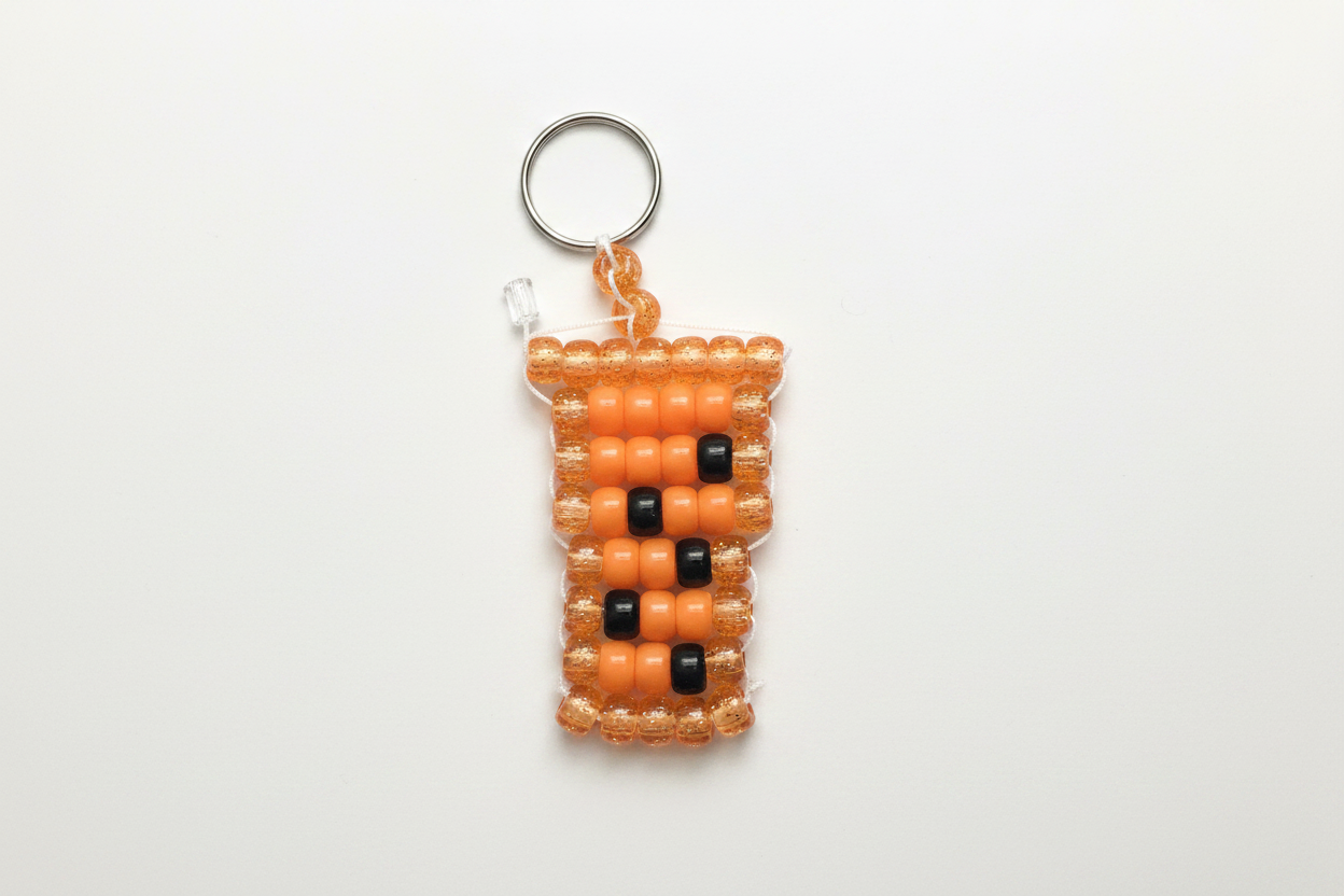 Handmade orange boba tea pony bead keychain on white background